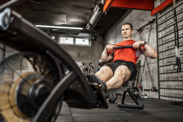 istock Man doing cardio workout on rowing machine in gym 1227136758