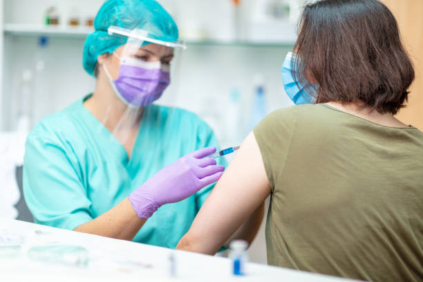 istock Nurse in protective workwear injecting flu vaccine into patient's arm 1227138044