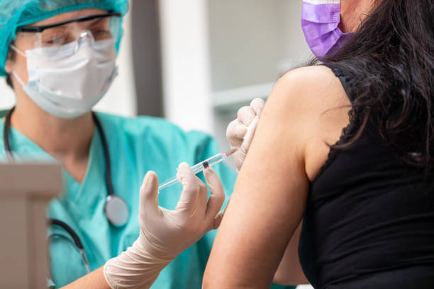 istock Female doctor in protective work-wear injecting flu vaccine 1227138095