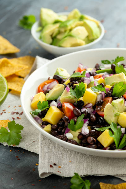 ensalada de aguacate, mango con frijol negro, tomate, cebolla roja y chips de tortilla. alimentos saludables - mango salsa fotografías e imágenes de stock