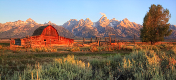 An old barn during sunrise with the Tetons in the background.