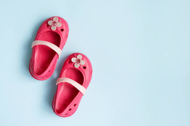 istock Baby pink rubber summer shoes on blue background with copy space 1227146428