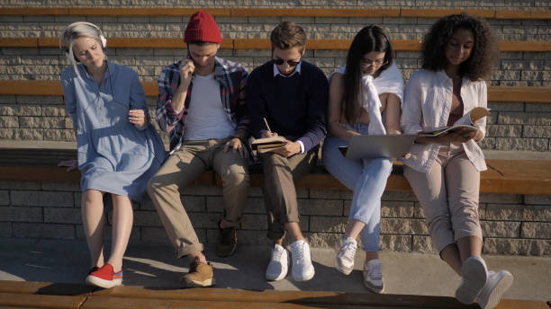 Five friends sitting together, each is busy with another activit