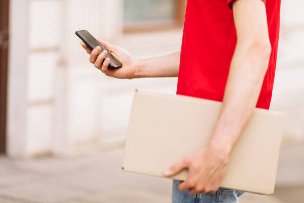istock a courier with a cardboard box using a mobile phone. Home delivery 1227148855
