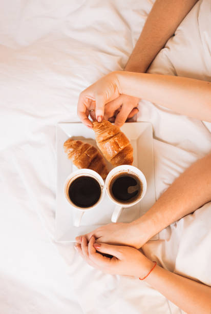 istock hands loving couple having Breakfast in bed with coffee and croissants. 1227149091