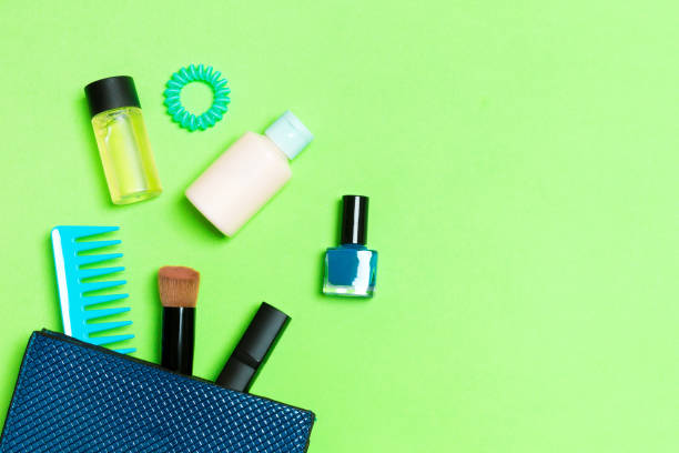 make up products spilling out of cosmetics bag on green background with empty space for your design - pampering nail polish make up spilling imagens e fotografias de stock