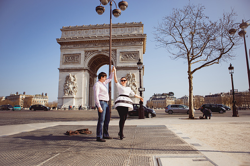 a married couple walk through Paris at the arc de Triomphe. honeymoon in the spring in France.