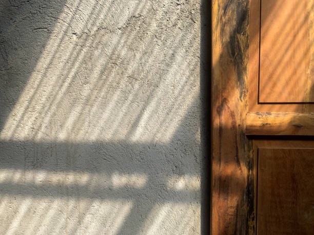 istock light and shadow from the window. Thin line of light on the wall. Plaster texture. Shadow from the curtain. Place for your text. color tone. wood texture of the door 1227150357