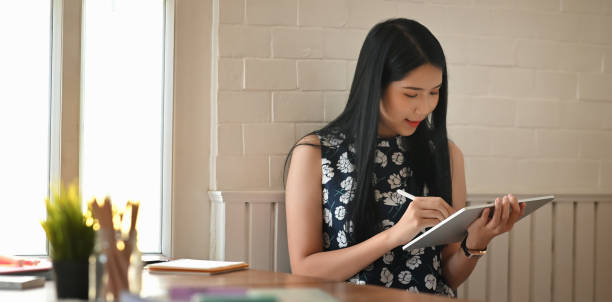 istock Woman drawing/sketching on computer tablet by using a stylus pen while sitting at the working desk over comfortable. 1227154360