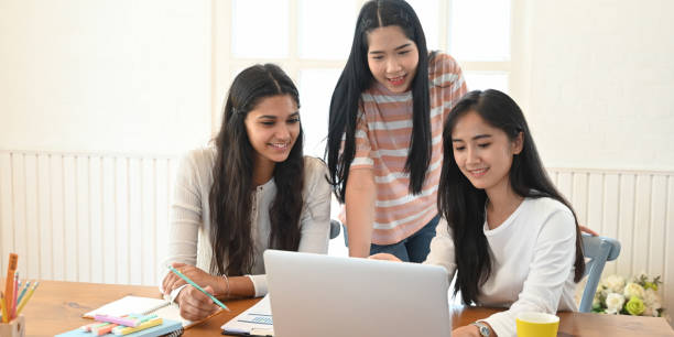 istock University students tutoring/studying online with video conference while sitting in front of computer laptop at the wooden working desk over comfortable bedroom as background. 1227155154