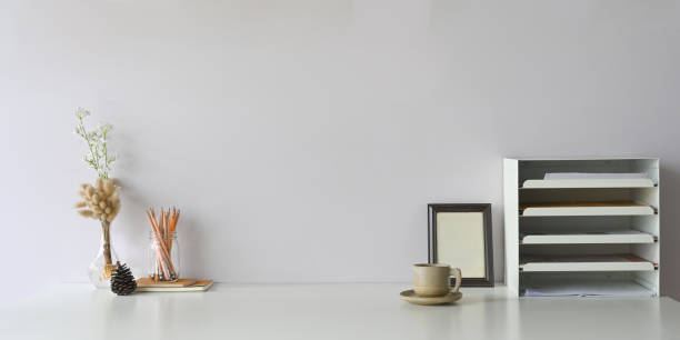 istock Workspace coffee cup that surrounded by document shelf, picture frame, pencils in glass vase, pine cone, notebooks and wild grass in bottle. 1227155711