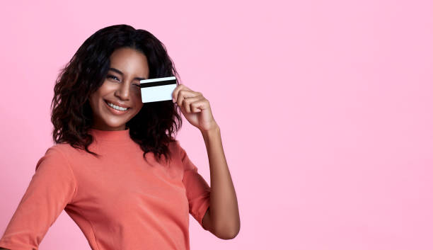 young smiling beautiful african woman showing credit card in hand over pink banner background with copy space. - 2554 imagens e fotografias de stock