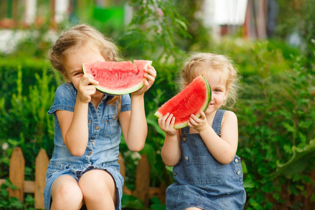 istock Little girls sit on watermelon and keep pieces 1227156248