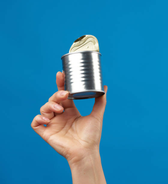 open metal round tin can in a female hand on a blue background