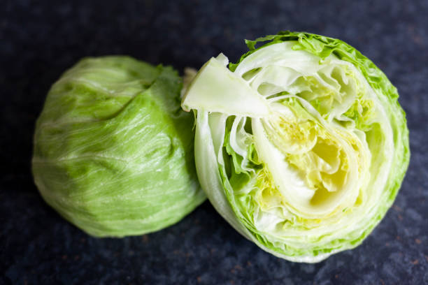 Iceberg lettuce, cut in half on a dark background Iceberg lettuce, cut in half on a dark background Iceberg Lettuce stock pictures, royalty-free photos & images