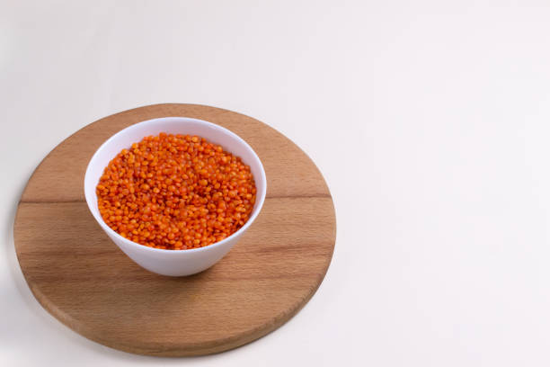 istock Orange lentils in a white bowl on a round cutting board. 1227168667