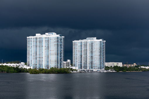 This is a photograph of  luxury residential buildings with dark tropical storm clouds developing in Miami, Florida at the beginning of hurricane season.