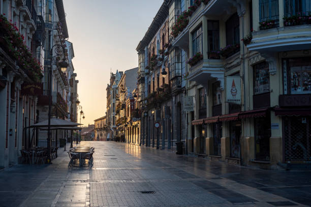 Empty street (Calle Ancha) at sunrise in the heart of Leon, Spain. Shuttered shops line both sides of the street.