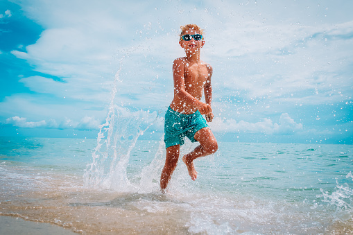happy kid run and splash water on beach vacation