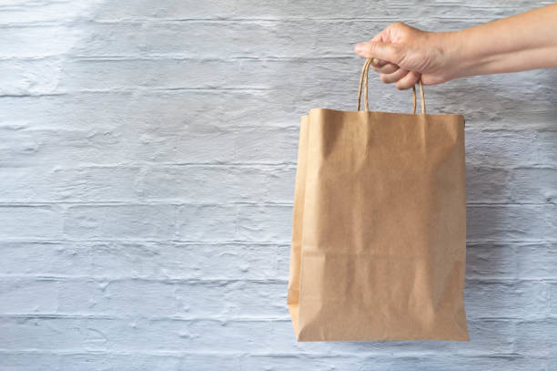 istock Hand holding cardboard bag on brick wall background 1227173314