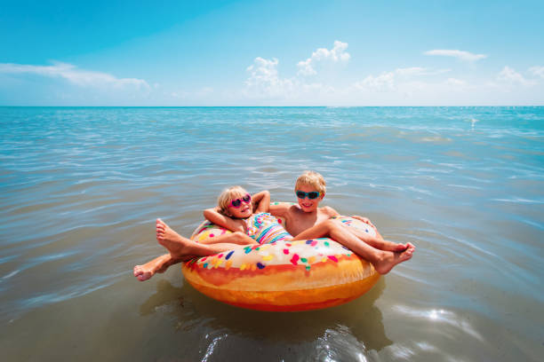 istock happy kids, boy and girl, swim on floatie at beach 1227174708