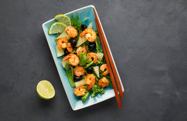 salad with shrimp, pineapple and fresh herbs in a blue plate on a black background. - prepared shrimp prawn seafood salad imagens e fotografias de stock