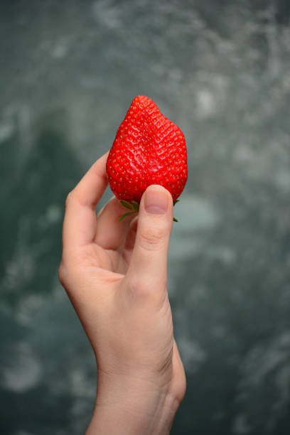 istock Woman holding a fresh strawberry in her hand 1227176455