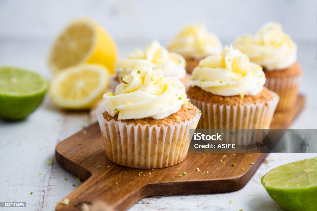 Lemon and poppy seed cupcakes with cheese cream frosting Lemon and poppy seed cupcakes with cheese cream frosting and lemon and lime zest on a cutting board Cupcake Stock Photo