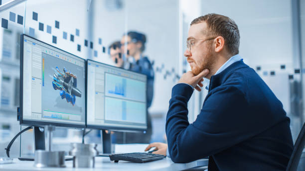 istock Industrial Engineer Working on a Personal Computer, Two Monitor Screens Show CAD Software with 3D Prototype of Hybrid Electric Engine and Charts. Working Modern Factory. 1227179651
