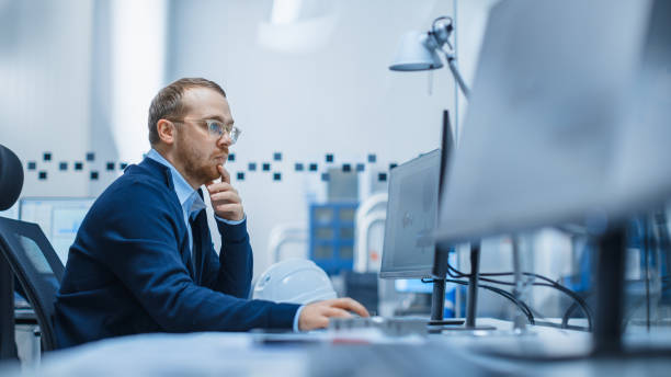 istock Shot of Male Industrial Engineer Solving Problems, Working on a Personal Computer, He is Working in Office in Modern Factory with High-Tech Machinery. 1227179676