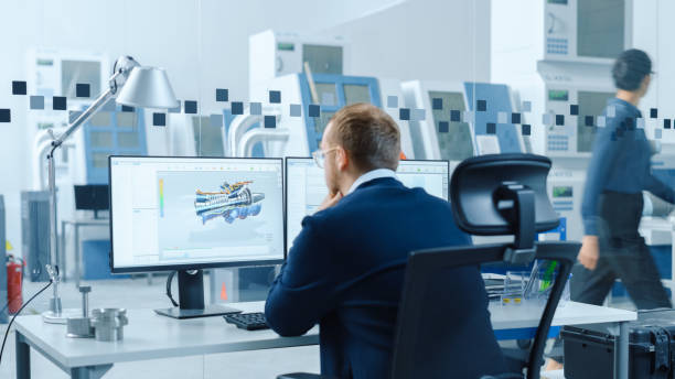 istock Industrial Engineer Solving Problems, Working on a Personal Computer, Two Monitor Screens Show CAD Software with 3D Prototype of Hybrid Electric Engine Being Tested. Working Modern Factory. 1227179756