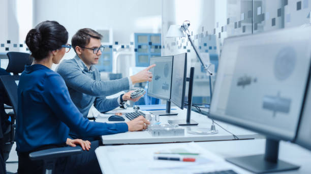 istock Modern Factory: Male Industrial Engineer Explains to Female Project Supervisor Functions of the Machine Part Comparing it to one on Computer Screen. They use CAD Software for Design, Development 1227179893