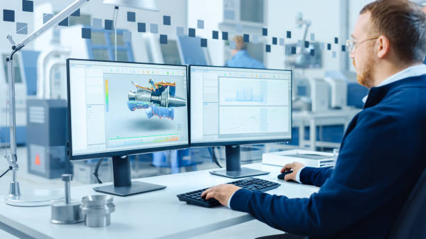 istock Industrial Engineer Working on a Personal Computer, Two Monitor Screens Show CAD Software with 3D Prototype of Hybrid Electric Engine and Charts. Modern Factory with High-Tech Machinery 1227179949