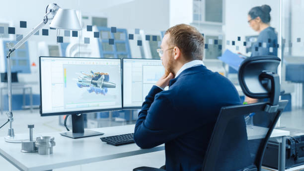 istock Industrial Engineer Working on a Personal Computer, Two Monitor Screens Show CAD Software with 3D Prototype of Hybrid Electric Engine and Charts. Working Modern Factory. 1227179958