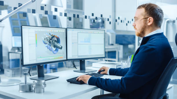 istock Industrial Engineer Working on a Personal Computer, Two Monitor Screens Show CAD Software with 3D Prototype of Hybrid Electric Engine and Charts. Modern Factory with High-Tech Machinery 1227180007