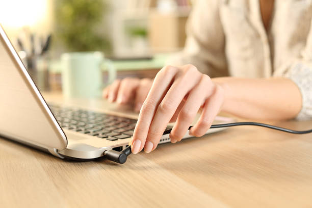 Woman hands plugging battery charger on laptop Woman hands plugging battery charger on laptop plugging in photos stock pictures, royalty-free photos & images