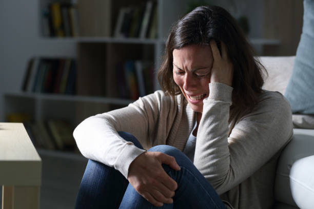 Sad middle age woman crying sitting in the night at home stock photo