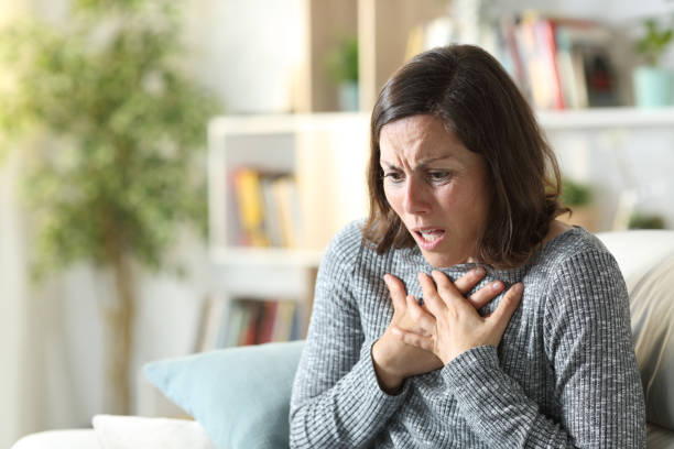 donna di mezza età che sibila toccando il petto a casa - soffocare foto e immagini stock