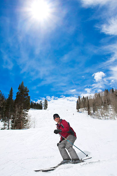 A male skier smiling as he skis downhill on a ski vacation in Park City, Utah. Lots of copy space
