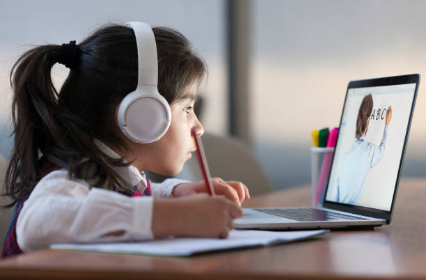 Little girl attending to online school class Little girl attending to online school class on laptop computer e learning stock pictures, royalty-free photos & images