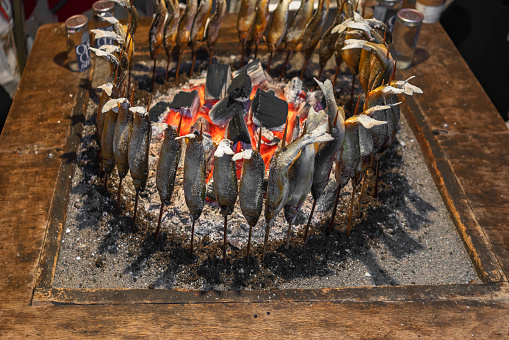 Japanese ayu fish skewers also called sweetfish grilled with salt and cooked in circle in a traditional robatayaki cooking around hot charcoals on a irori sunken hearth.