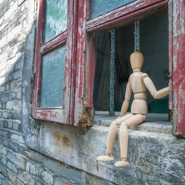 istock A wooden mannequin sitting on a old broken window,lonely scene. 1227188023