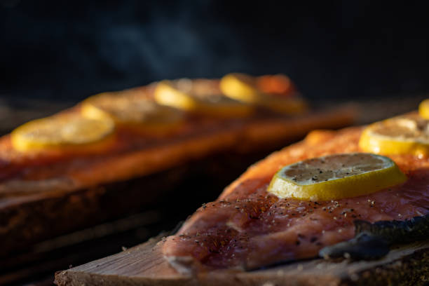 Salmon fish with lemon wedges and pepper grilling in the orange sunset