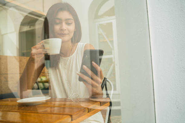 istock Young latin woman using phone at coffee shop. 1227193902