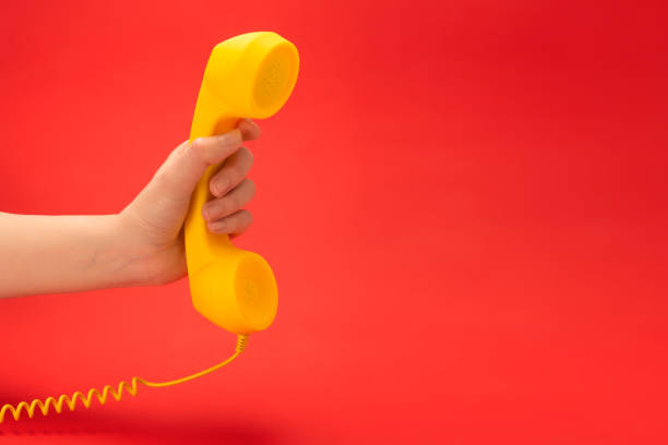 istock Yellow handset on a red background in woman hand. 1227195302