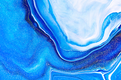 Fluid art texture. Abstract background with iridescent paint effect. Liquid acrylic artwork with flows and splashes. Mixed paints for baner or wallpaper. Blue, golden and white overflowing colors
