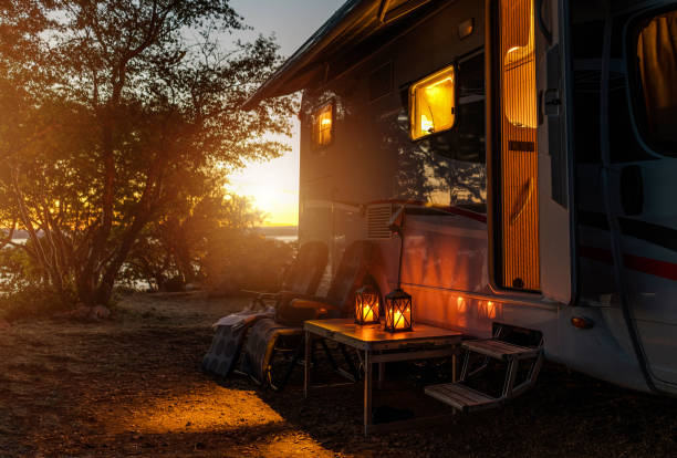 RV Camper Van Camping Warm Night Road Trip Adventures. Calm Warm Night on a Camping. Camper Van, Outdoor Chairs and Romantic Light From Lanterns. Vacation in Recreational Vehicle. camping stock pictures, royalty-free photos & images