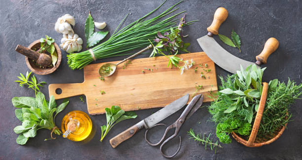 Various fresh herbs from garden with kitchen utensils on rustic table. Top view with copy space