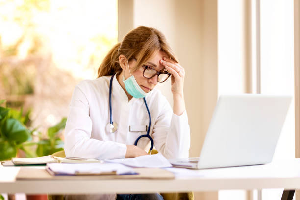istock Female doctor having a headache while being at doctor's office and working on laptop 1227200327