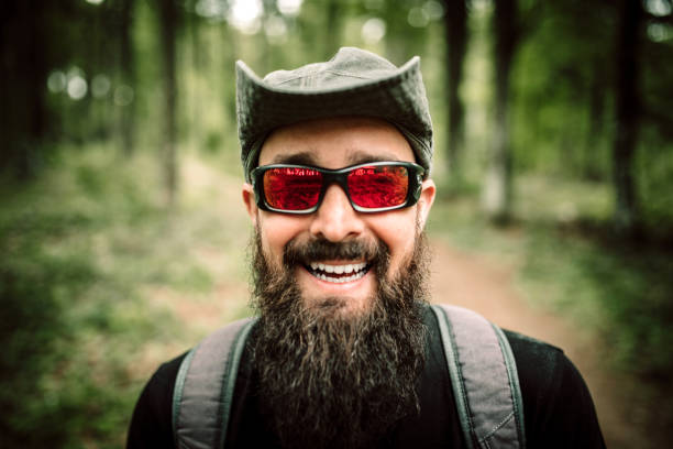 Hiker in the mountain wearing sunglasses, hat and backpack. Happy and active man.